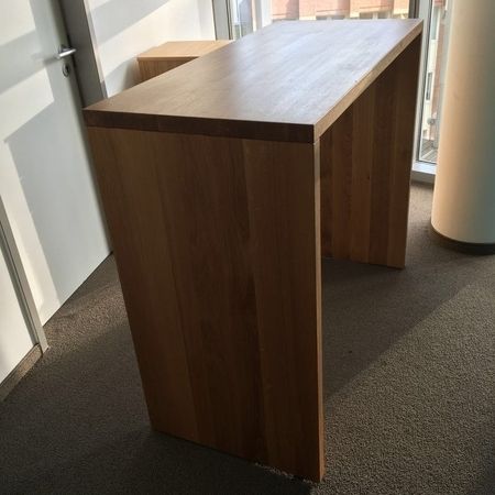 Ein Holztisch in einem Büroumfeld, umgeben von Stühlen und Büroaccessoires.