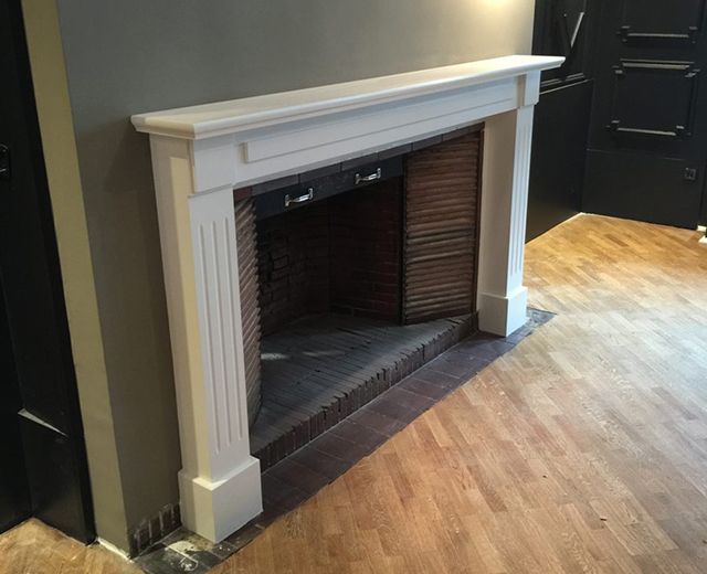 Kamin mit Ziegelumrandung auf einem Holzboden.